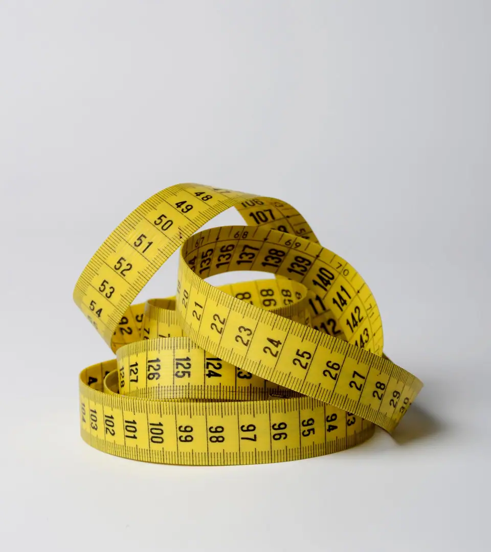 A coiled yellow tape measure on a white surface